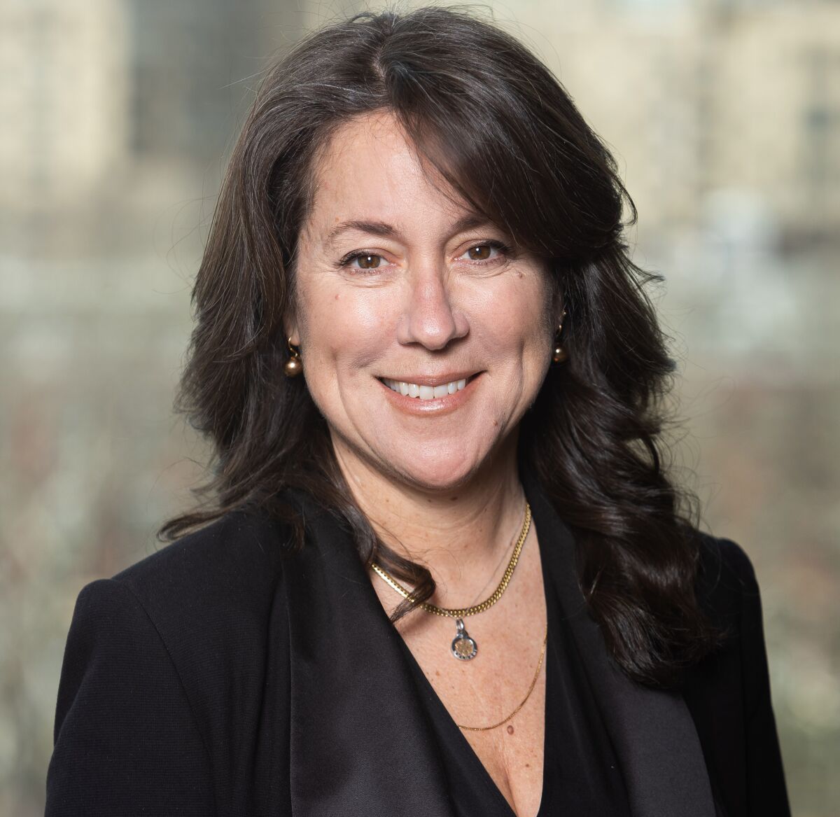 A smiling woman in a dark V-neck shirt.