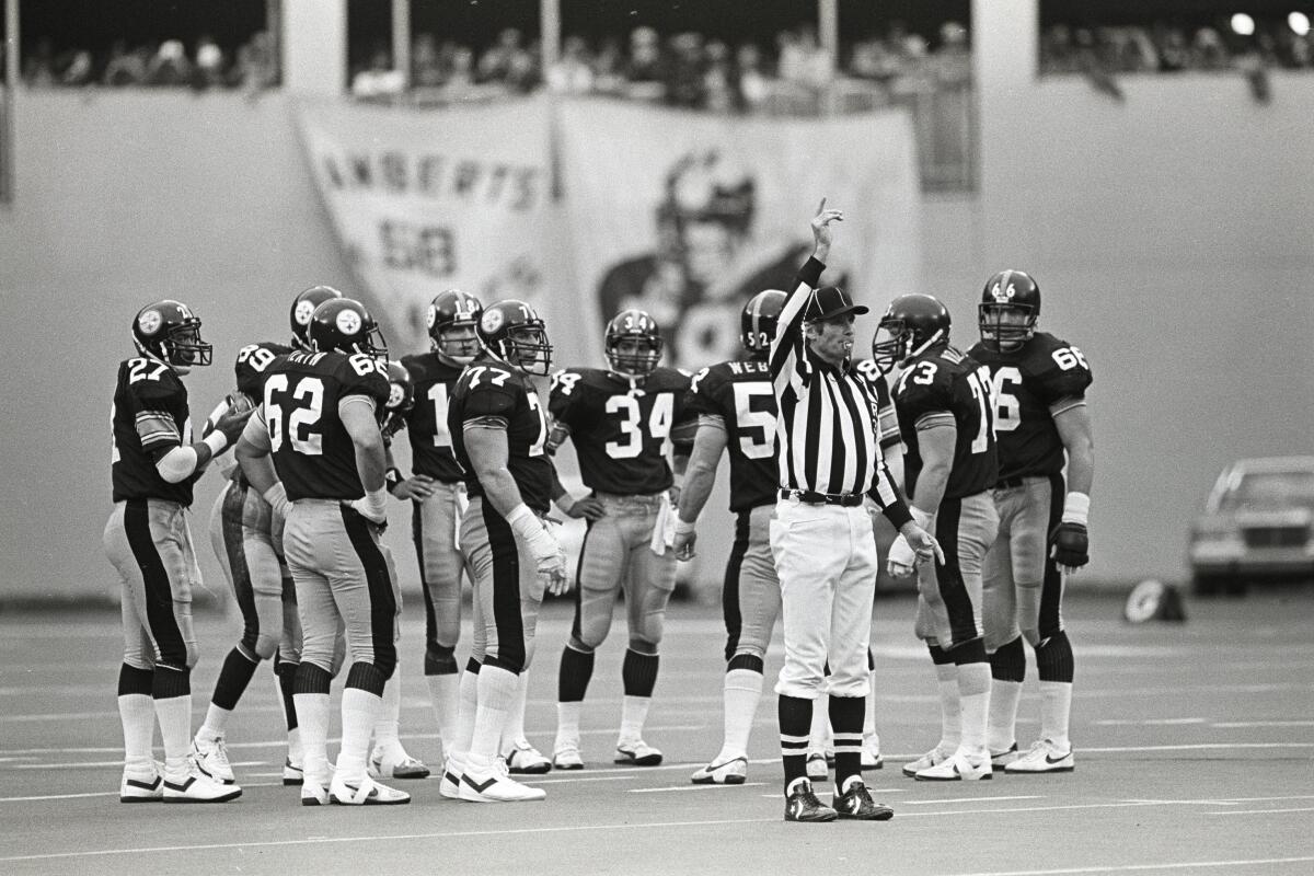 NFL referee Jim Tunney signals while standing near the Steelers huddle during a game at Three Rivers Stadium in 1983.