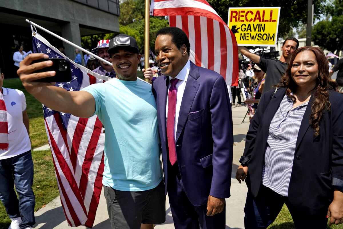 Radio talk show host Larry Elder, center, poses for selfies with supporters