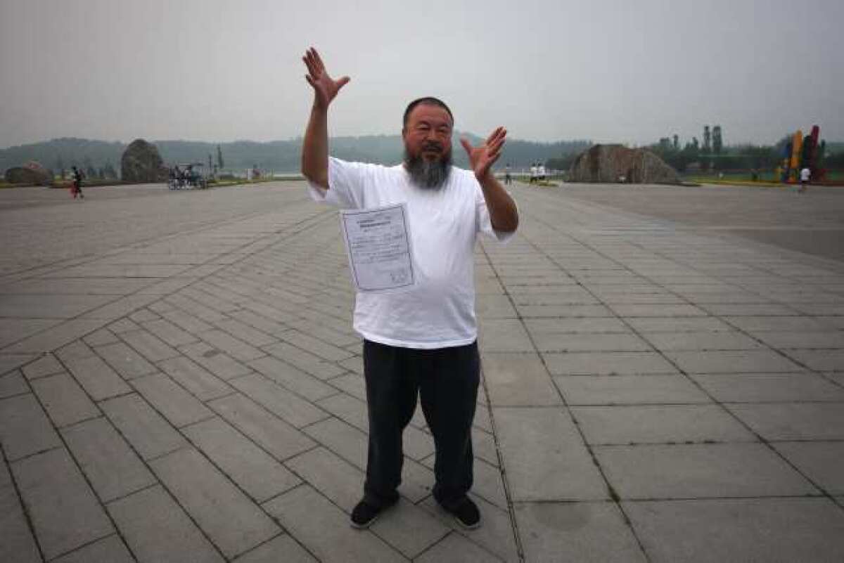 Ai Weiwei drops a copy of a government document informing him of the expiration of his bail term in a park in Beijing on Thursday.