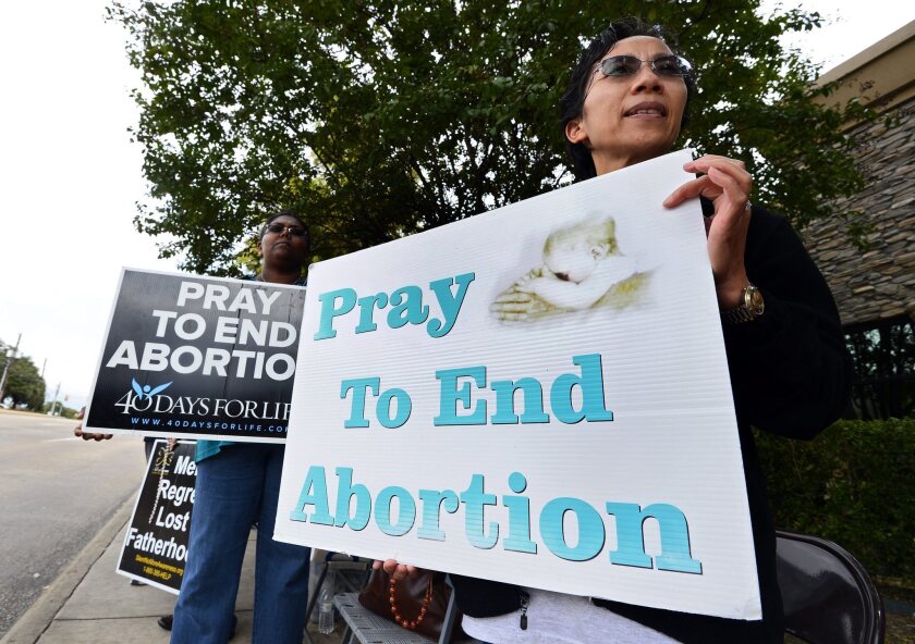 Protesters stand with signs along the street in front of Southwestern Women's Surgery Center in Dallas in October 2013. The threat of similar protests led another hospital to revoke the access it had given two abortion-performing doctors, a lawsuit filed this week argues.