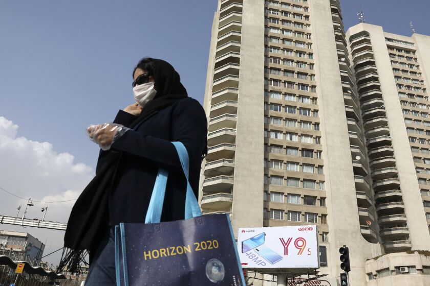 A pedestrian wearing a face mask crosses a street in northern Tehran, Iran, Sunday, March 1, 2020. While the new coronavirus has extended its reach across the world, geographic clusters of infections were emerging, with Iran, Italy and South Korea seeing rising cases. (AP Photo/Vahid Salemi)