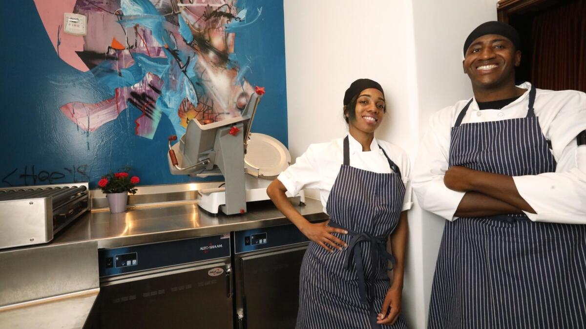 Cooks Marcus Lewis and Zia Hughes stand inside the take-away area of APL restaurant in Hollywood.