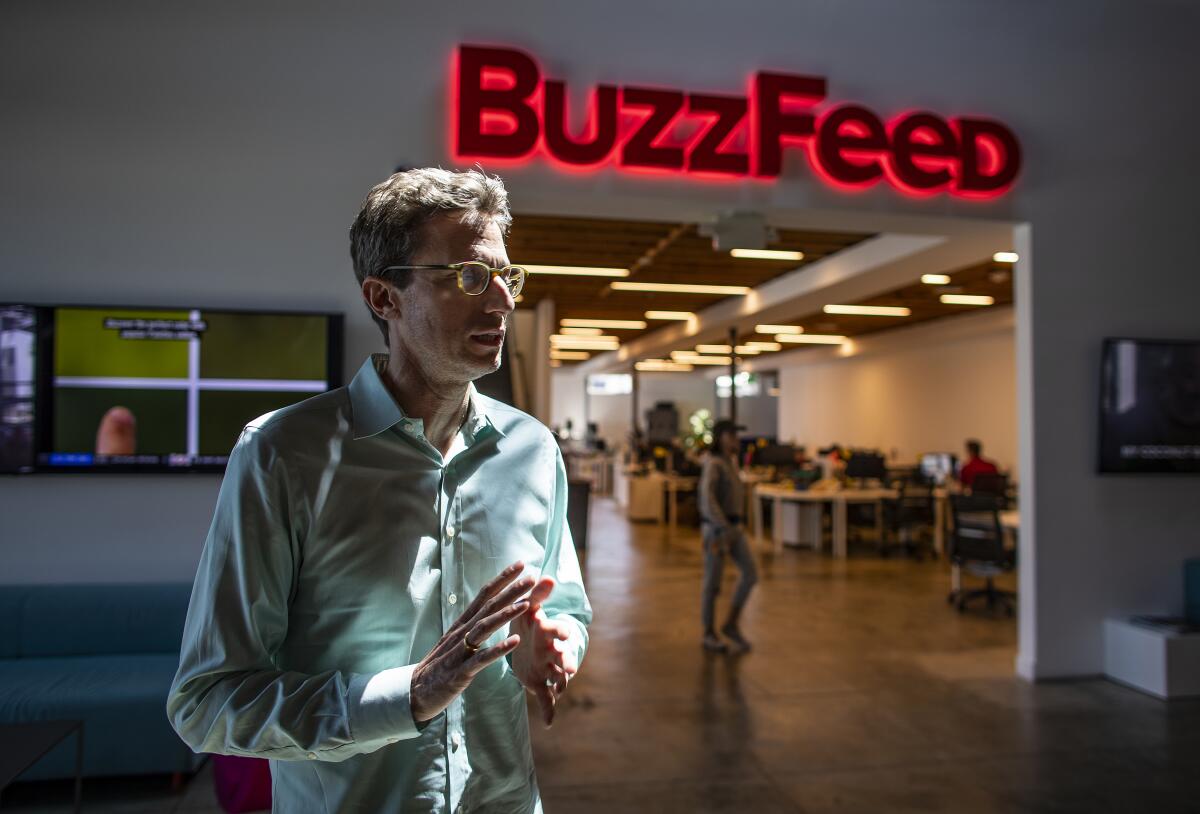 BuzzFeed CEO Jonah Peretti in Los Angeles under a red neon sign that says BuzzFeed