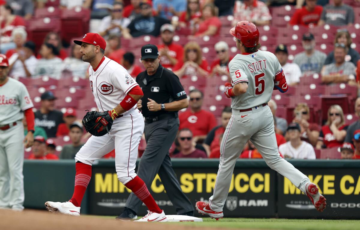 Cincinnati Reds first baseman Joey Votto, left, gets an out at first on Philadelphia Phillies Bryson Stott during the first inning of a baseball game in Cincinnati on Tuesday, Aug. 16, 2022. (AP Photo/Paul Vernon)
