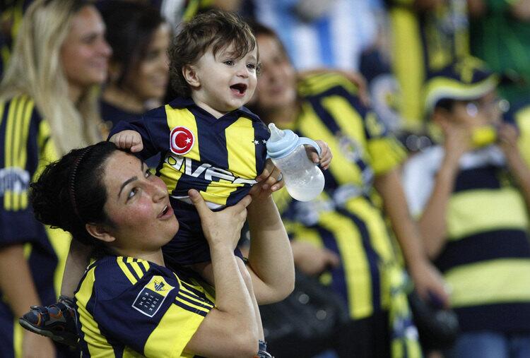 A Fenerbahce fan holds a baby as she watches the Turkish Super League soccer match between Fenerbahce and Manisaspor at Sukru Saracoglu stadium in Istanbul.