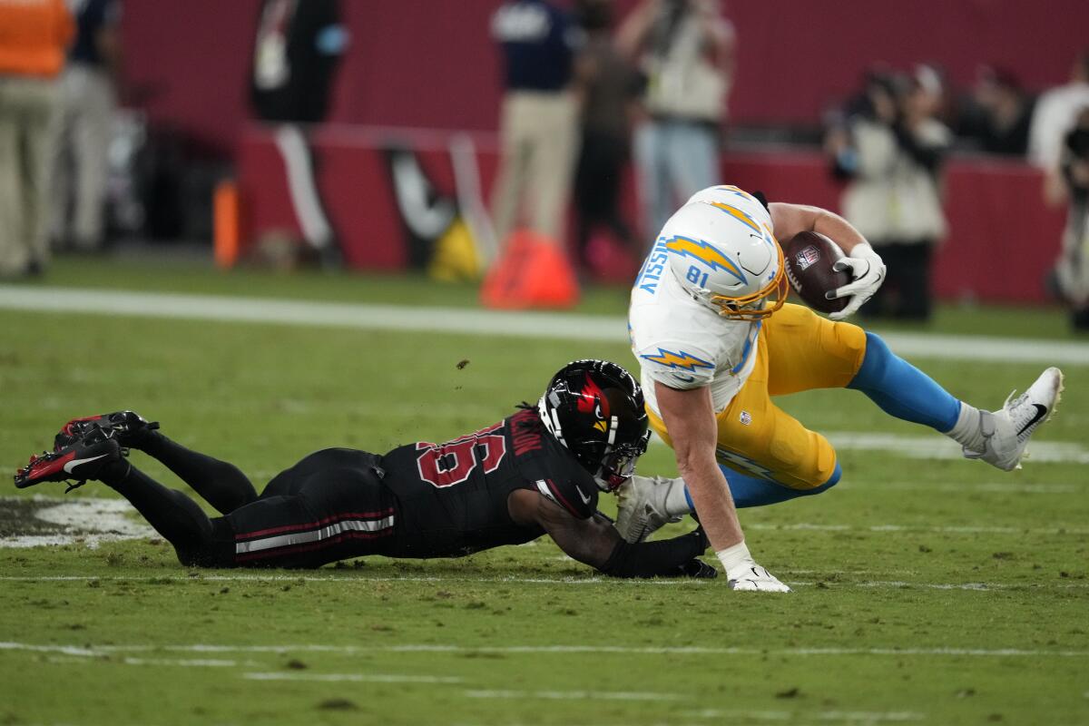 Chargers tight end Will Dissly holds the ball and reaches for the ground while being tackled