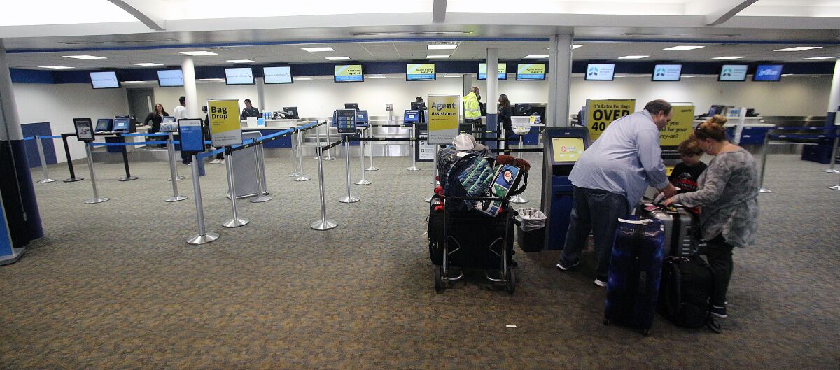 A family completes their self check-in while nearly all other lines are empty at the Hollywood Burbank Airport on Tuesday, March 17. The number of passengers at the airport were diminished by 50% or more due to the coronavirus outbreak.