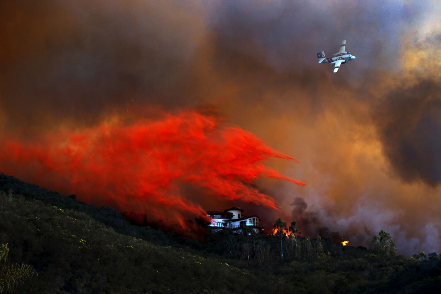 An airplane makes a fire retardant drop around a large Coronado Hills home in the San Marcos area.
