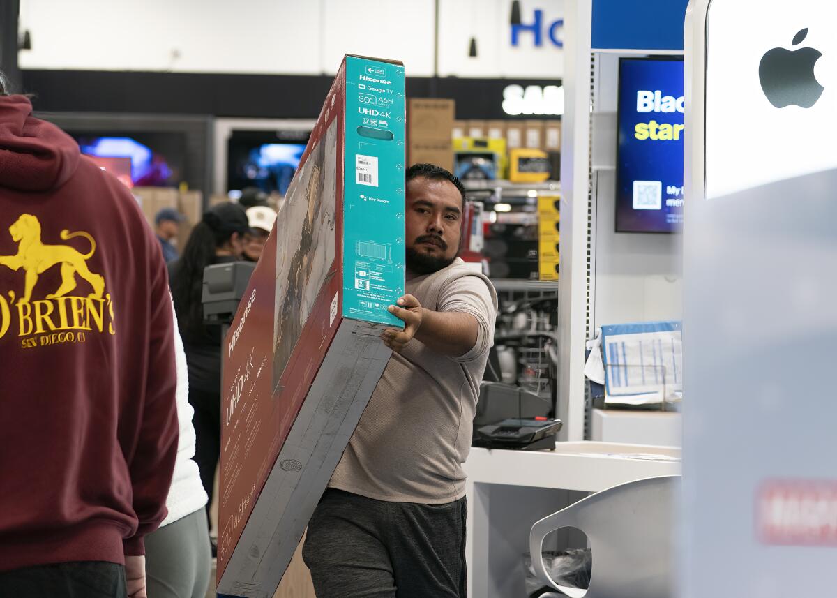 Roberto Hernandez carries out his new 50-inch flat-screen TV he purchased during Black Friday deals.