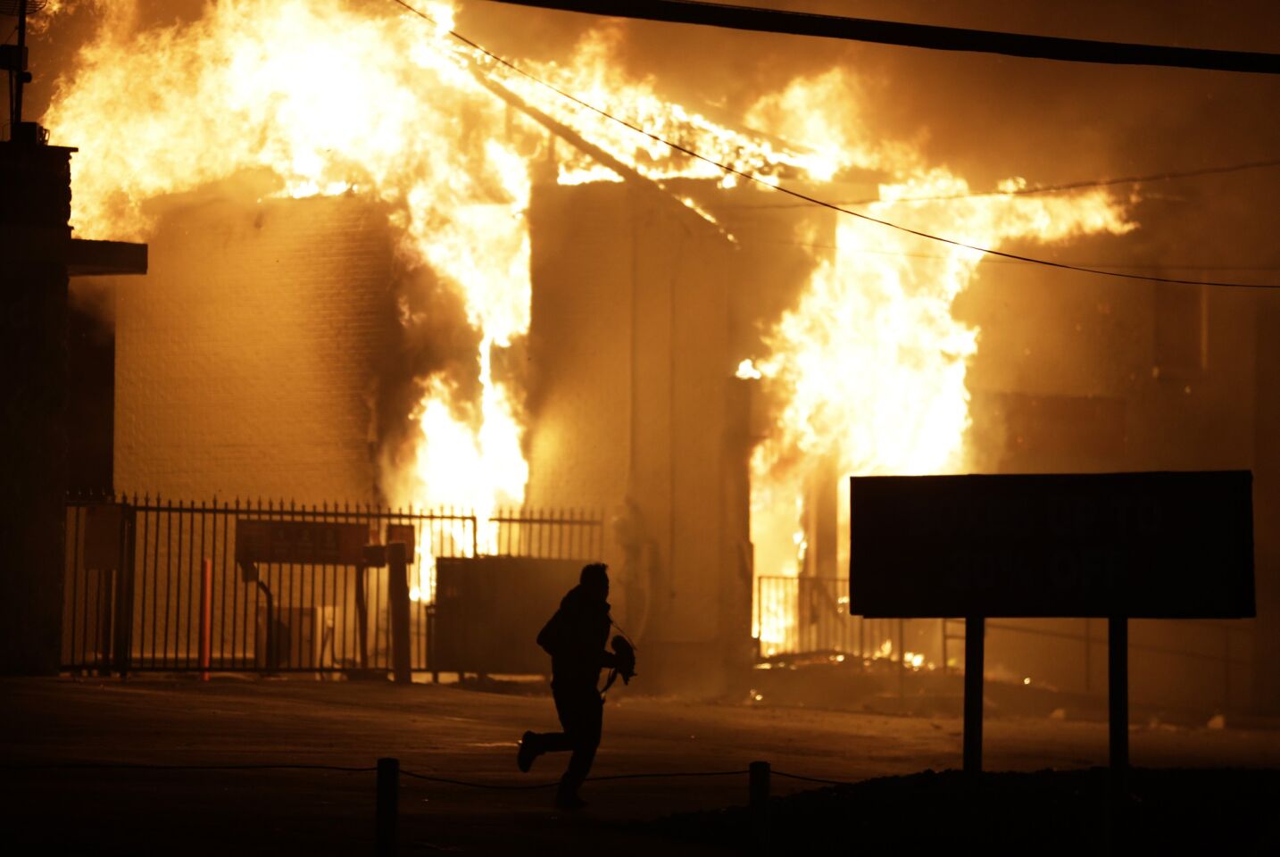 A man runs away from a burning storage facility in Ferguson, Mo., after the announcement of the grand jury decision.