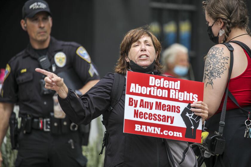 Santa Monica, CA - July 16: A Santa Monica police officer watches as River Huston chants pro abortion-rights slogans at rally at Planned Parenthood-Santa Monica Health Center on Saturday, July 16, 2022 in Santa Monica, CA. (Irfan Khan / Los Angeles Times)