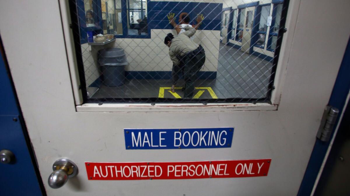 A sheriff's deputy prepares a prisoner for booking at the Fresno jail facility.