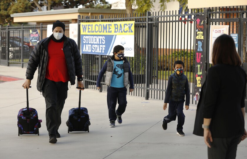 A father carries his sons' backpacks to Alta Vista Elementary School in Redondo Beach as classes resumed last month.