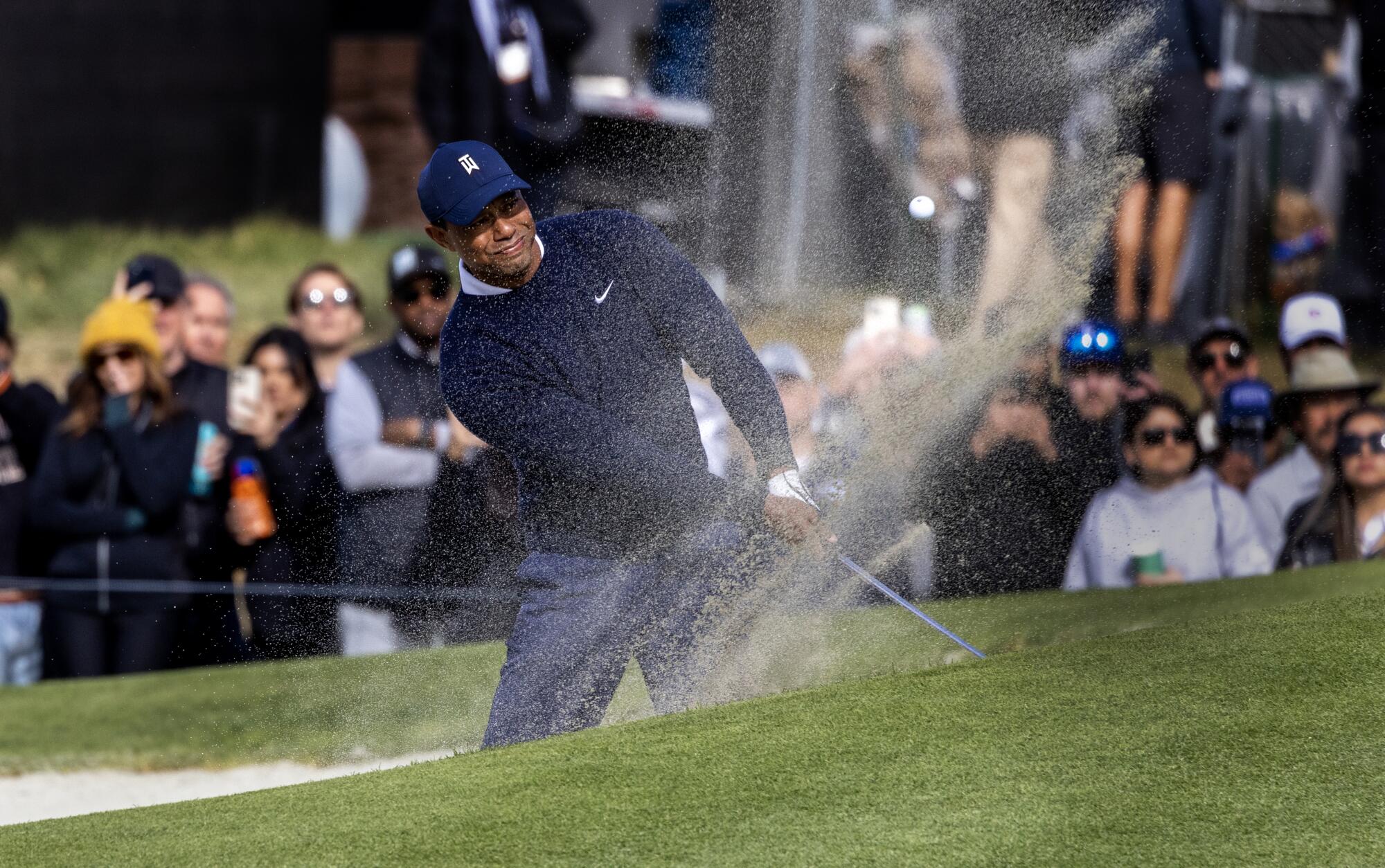 Tiger Woods hits out of the greenside bunker on the 10th hole during the first round.