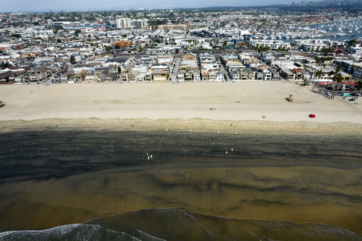 FILE - In this aerial image taken with a drone, workers in protective suits clean the contaminated beach after an oil spill in Newport Beach, Calif., on Wednesday, Oct. 6, 2021. A Los Angeles federal grand jury on Wednesday, Dec. 15 charged a Houston-based oil company and two subsidiaries for the oil spill off the California coast in October. (AP Photo/Ringo H.W. Chiu, File)