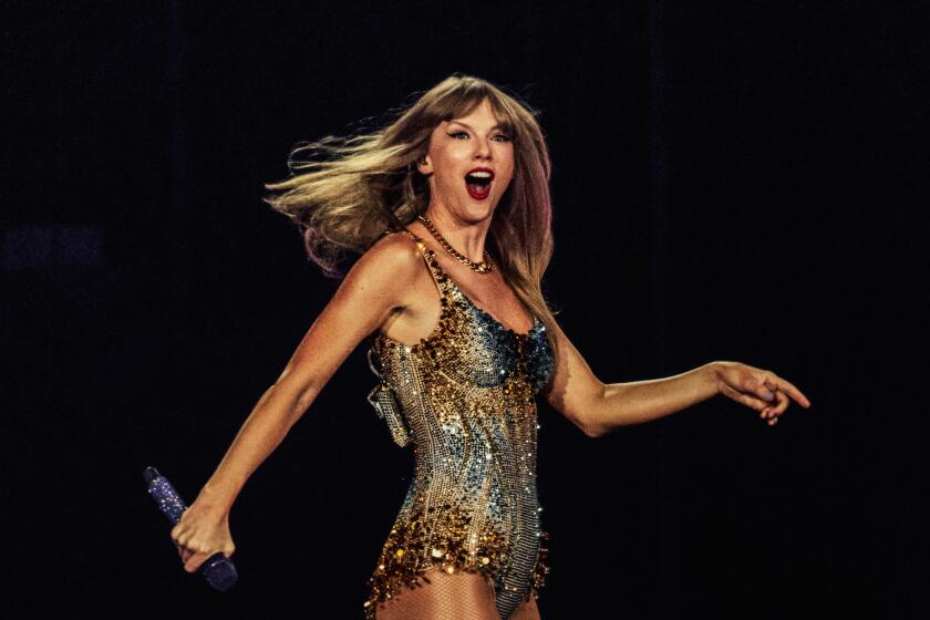 Taylor Swift is performing on stage with here mouth agape, smiling with a mic in hand, dressed in a rhinestone leotard