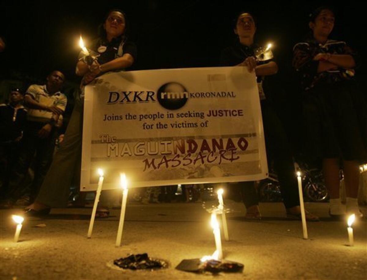 Members of a local radio hold streamers during a candle lighting rally in Koronadal city, south Cotabato province, southern Philippines on Wednesday, Nov. 25, 2009 to protest recent killings in Maguindanao. Officials recovered 11 more bodies Wednesday, six in a large pit buried with the wrecks of three vehicles and five in a third mass grave, bringing the death toll in Monday's attack on an election caravan to at least 57. (AP Photo/Aaron Favila)