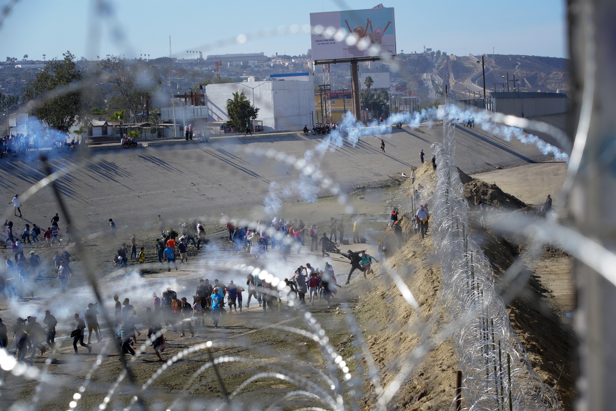 Seen through concertina wire, U.S. Border Patrol deploy CS gas on migrants at the U.S. - Mexico border near San Ysidro.
