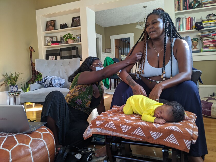 Midwife Kiki Jordan examines TaNefer Camara during a postnatal visit about a week after the birth of her son Esangu.