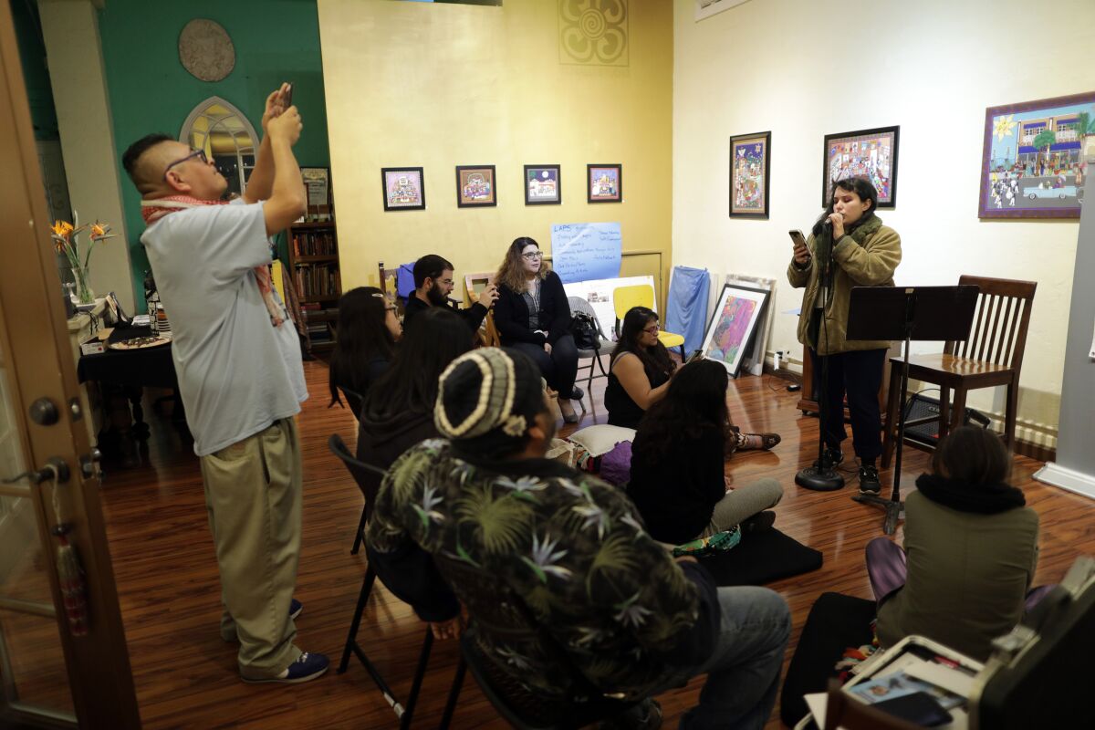 Viva Padilla, right, is the founder of Dryland, a literary journal that for four years has told stories of South-Central L.A. Nikolai Garcia, left, taking a photo, is a South-Central-raised poet and her assistant editor.