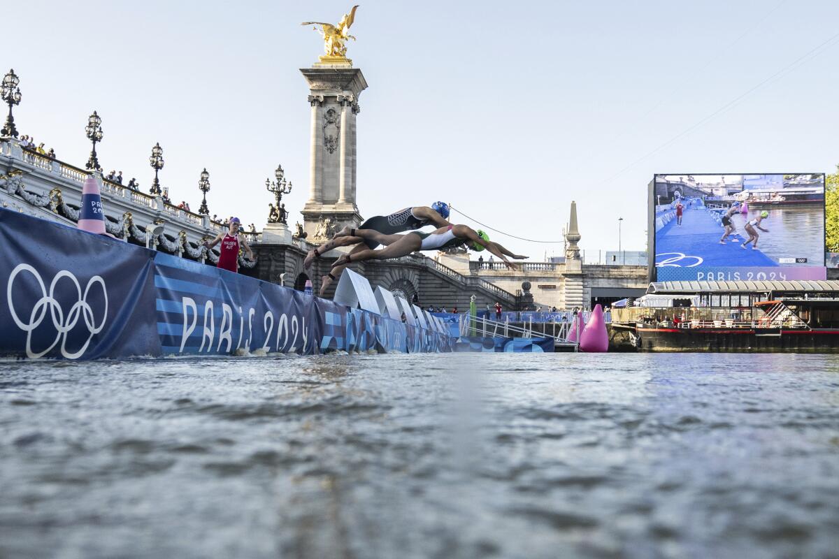 Athletes dive into the Seine River during the Olympic mixed relay triathlon on Monday.