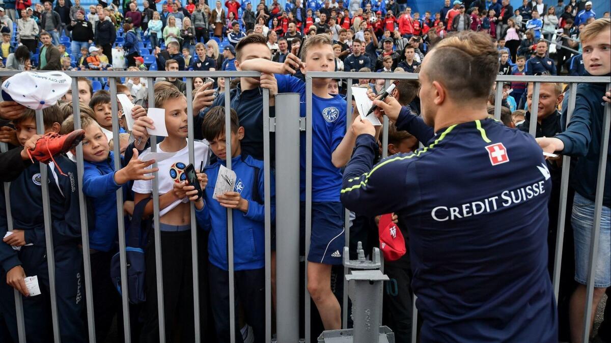 Switzerland's midfielder Xherdan Shaqiri signs autograph from behind a fence during a public training session in Tolyatti also know as Togliatti.