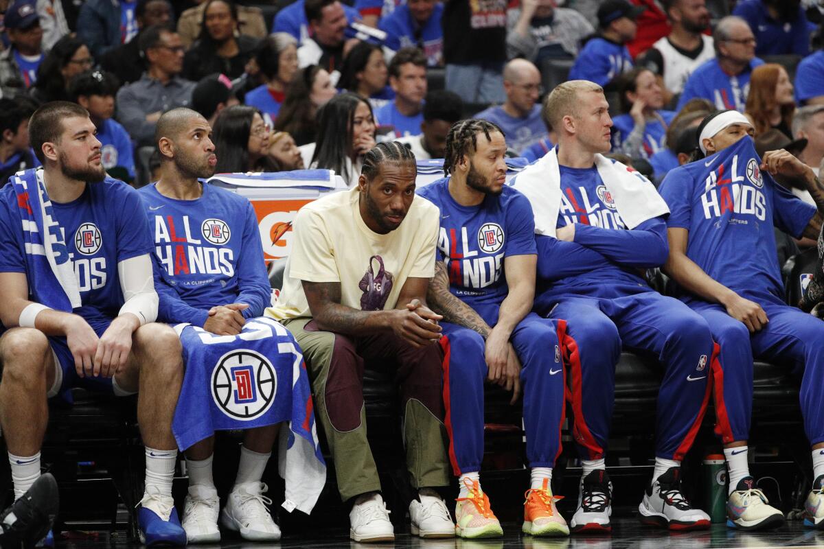 Kawhi Leonard (white T-shirt) sits with teammates on the Clippers bench on Thursday.