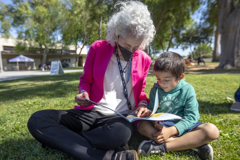 LOS ANGELES, CA - MAY 05: Director Barbara Ferrer, Los Angeles County Department of Public Health (Public Health) left, reads to Joshua Fernandez, 5, in Ted Watkins Memorial Park on Thursday, May 5, 2022 in Los Angeles, CA. CDC Director Dr. Rochelle Walensky and Barbara Ferrer were visiting a vaccination and testing site in the park. An outreach team from the site vaccinated several children and their parents outside in the park and Ferrer and Walensky looked on. The children each received a book after being vaccination Ferrer took an extra few minutes to read to Joshua. (Francine Orr / Los Angeles Times)