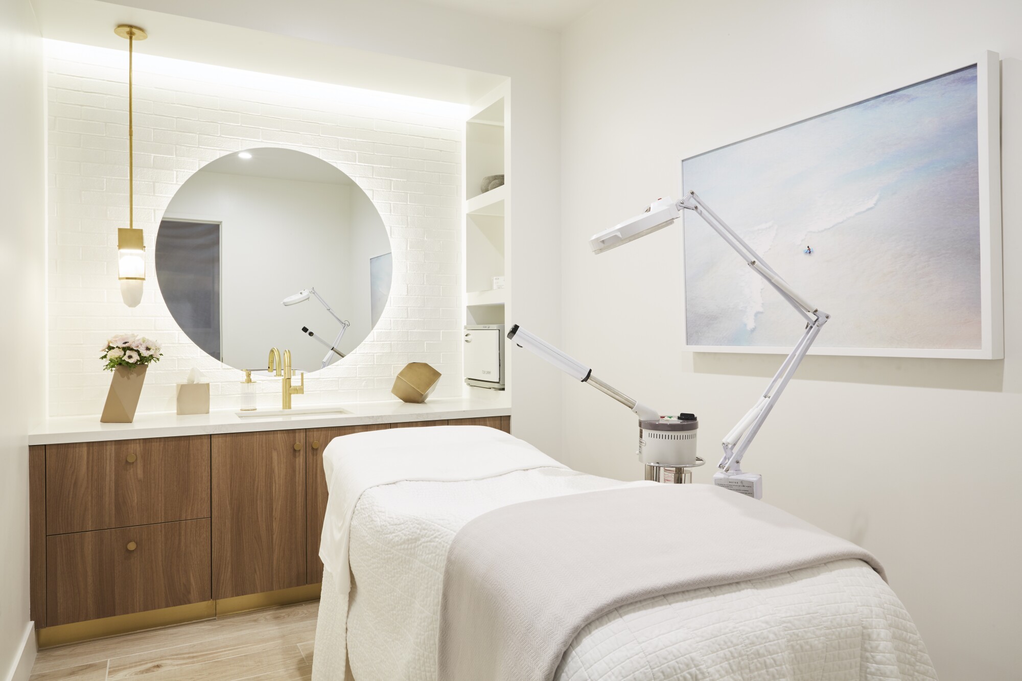 एक स्पा में सफ़ेद, चमकदार रोशनी वाले कमरे में उपचार बिस्तर