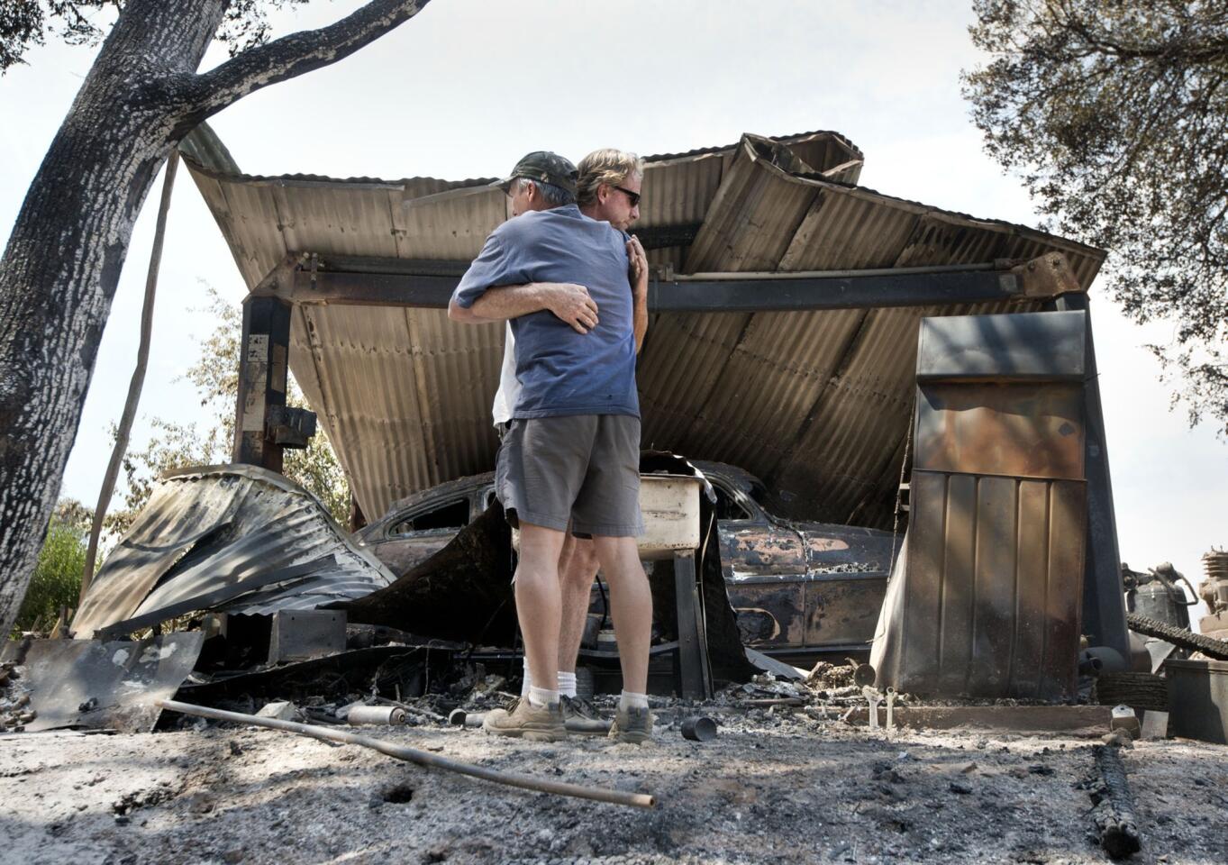 Bill Cleek, left, embraces his good friend Terry Cromwell outside a structure that housed one of many antique cars destroyed by a fire at Rancho Cicada Retreat in Plymouth, Calif. Many people in the area have been evacuated and several homes have been destroyed.