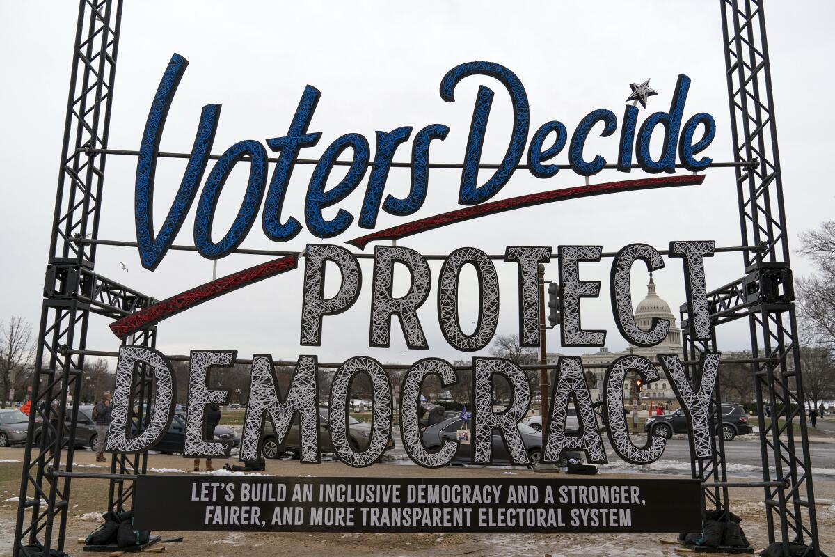 A large sign outside the Capitol reads "Voters Decide: Protect Democracy." 