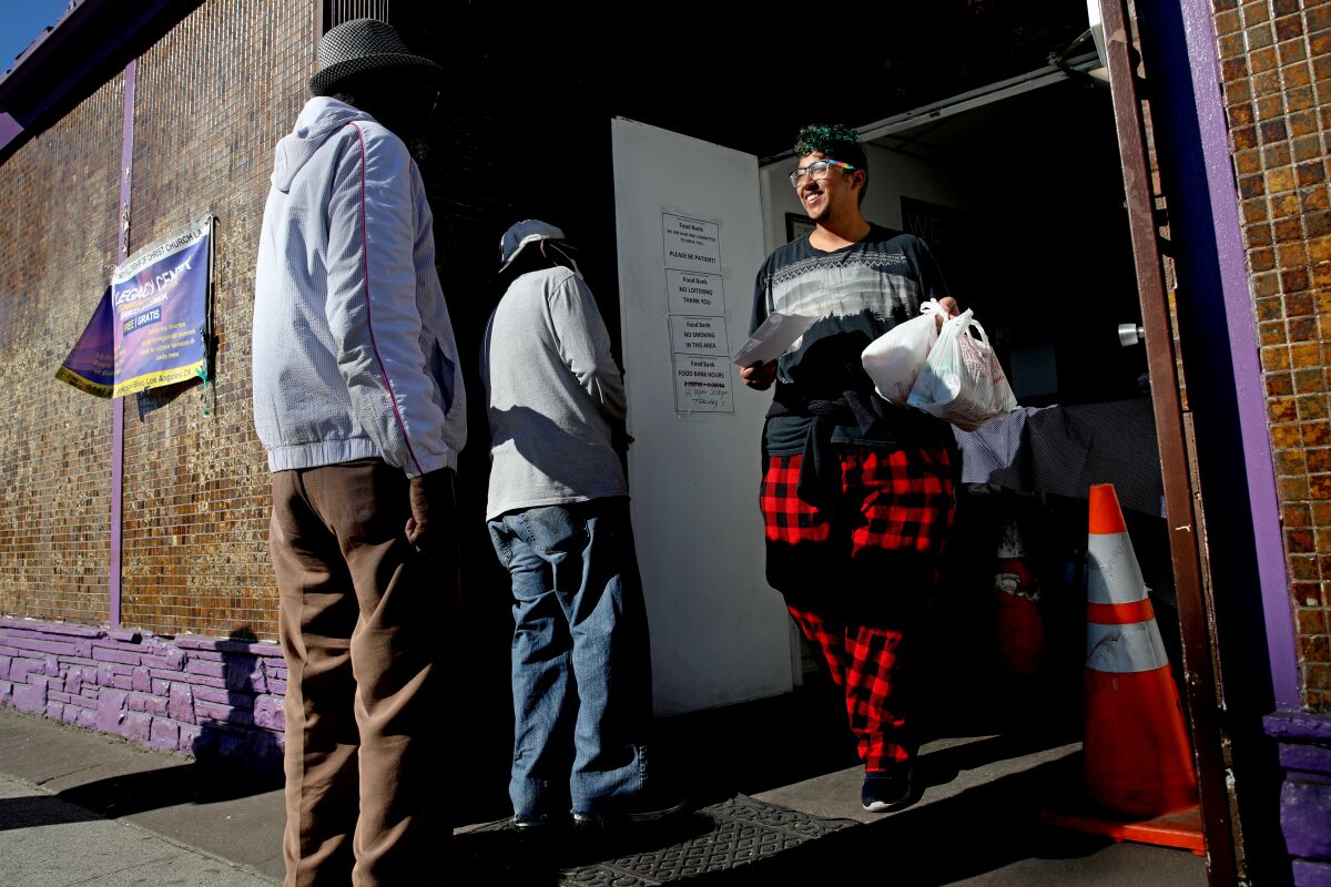Anthony Daniel, à droite, part avec des sacs de nourriture lors d'une distribution dans une banque alimentaire de Los Angeles