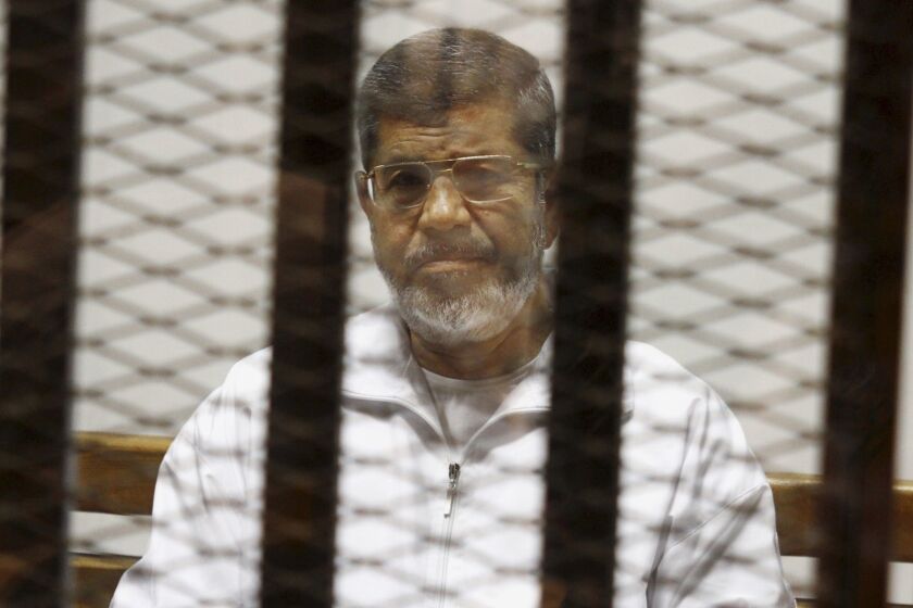 FILE - In this May 8, 2014 file photo, Egypt's ousted Islamist President Mohammed Morsi sits in a defendant cage in the Police Academy courthouse in Cairo, Egypt. Morsis collapse and death in a Cairo courtroom on June 17, 2019, was a brief rallying point for the Muslim Brotherhood whose influence waned dramatically in the Middle East since the 2013 military coup in Egypt which had widespread public support at the time. The long-running enmity between the Brotherhood and most Sunni-led governments highlights the deep divisions among Sunni Muslims. It adds a further complication to the volatile region, where the split between Sunnis and Shiite Muslims has created rival camps. (AP Photo/Tarek el-Gabbas, File)