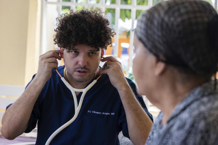Dr. Pedro Juan Vázquez, better known by his stage name PJ Sin Suela, attends to a patient in Loiza, Puerto Rico, Saturday, May 25, 2024. The 34-year-old doctor travels from the San Juan capital to the island’s southern and central regions to treat communities struggling in the aftermath of hurricanes. After hanging up his doctor’s scrubs, Vázquez spends his time producing new music that relays the island’s issues. (AP Photo/Alejandro Granadillo)