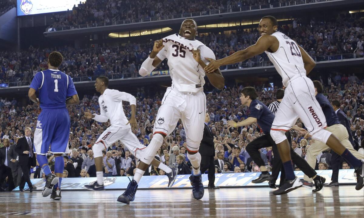 Connecticut players including center Amida Brimah (35) and guard Lasan Kromah (20) celebrate as Kentucky guard James Young (1) leaves the court at the end of the NCAA Tournament college basketball championship game last year in Arlington, Texas. Connecticut won 60-54.