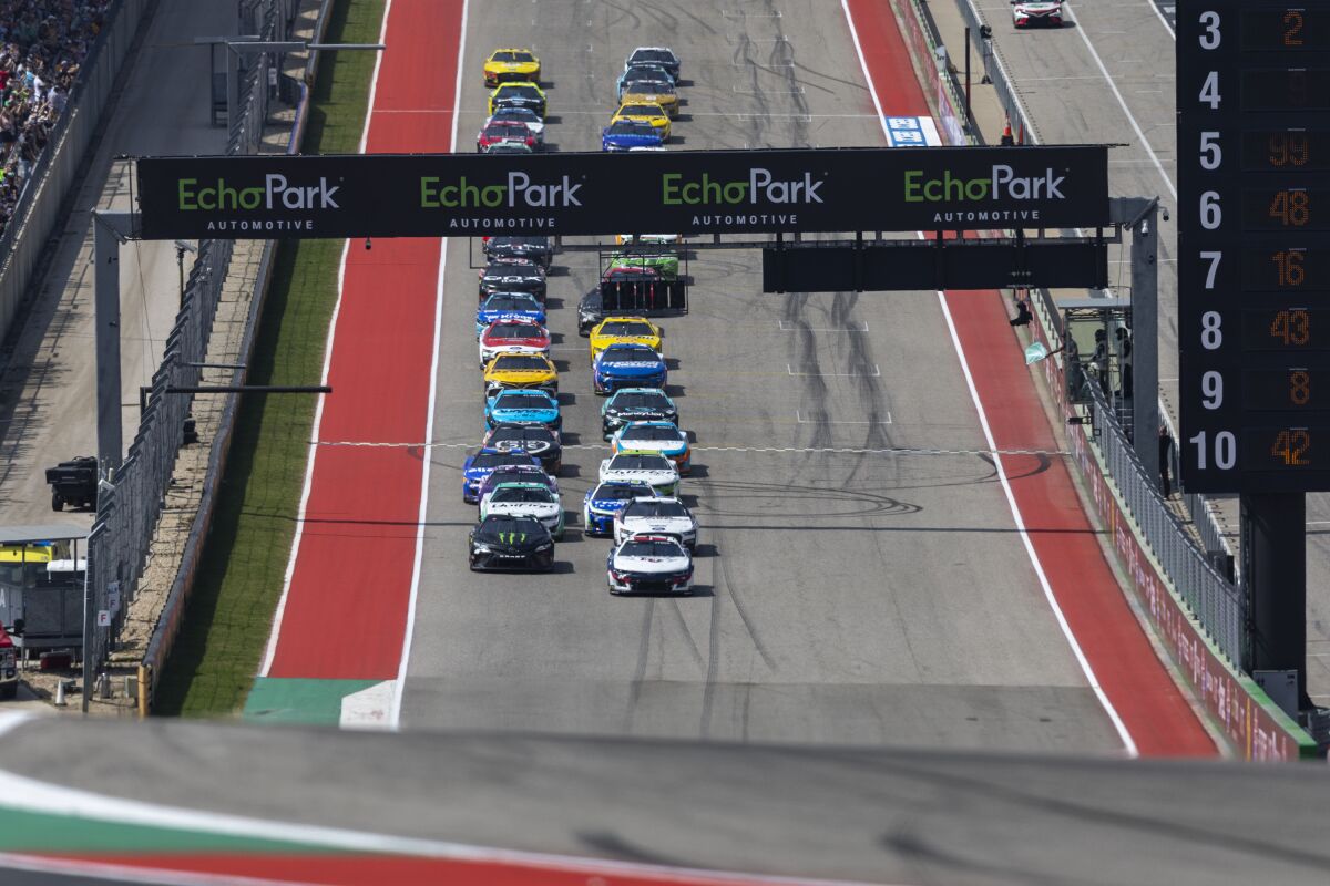 Tyler Reddick, left, and William Byron lead the beginning of the NASCAR Cup Series auto race at Circuit of the Americas, Sunday, March 26, 2023, in Austin, Texas. (AP Photo/Stephen Spillman)