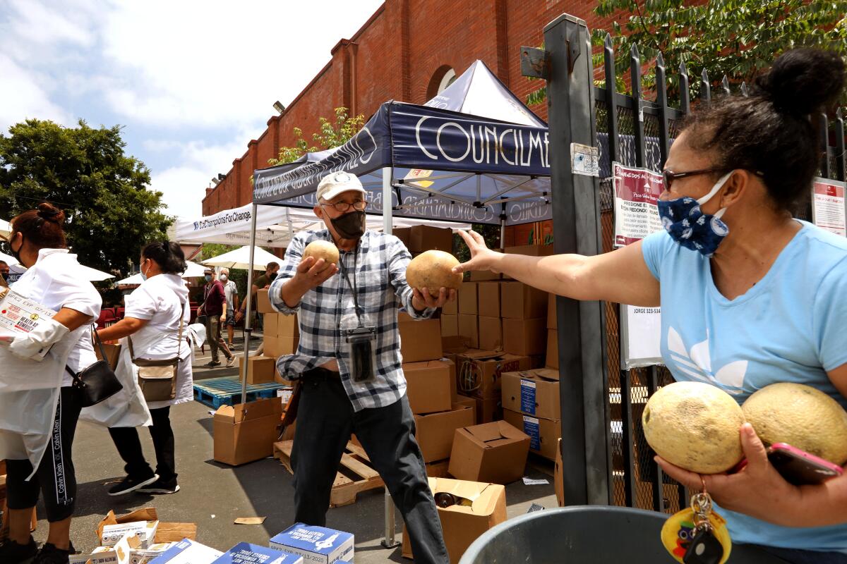 Jorge Alvarez, center, hands out produce to a  resident at the Pico Union Project in Los Angeles.