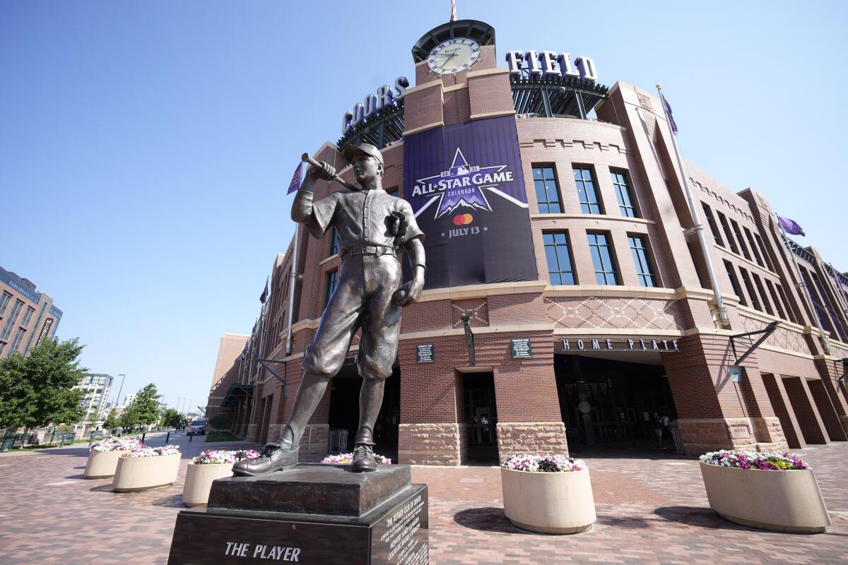 An All-Star Game banner hangs from the front entrance of Coors Field behind "The Player" sculpture.