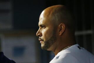 Dodgers first baseman Albert Pujols gets instruction from a coach in a game against the Arizona Diamondbacks