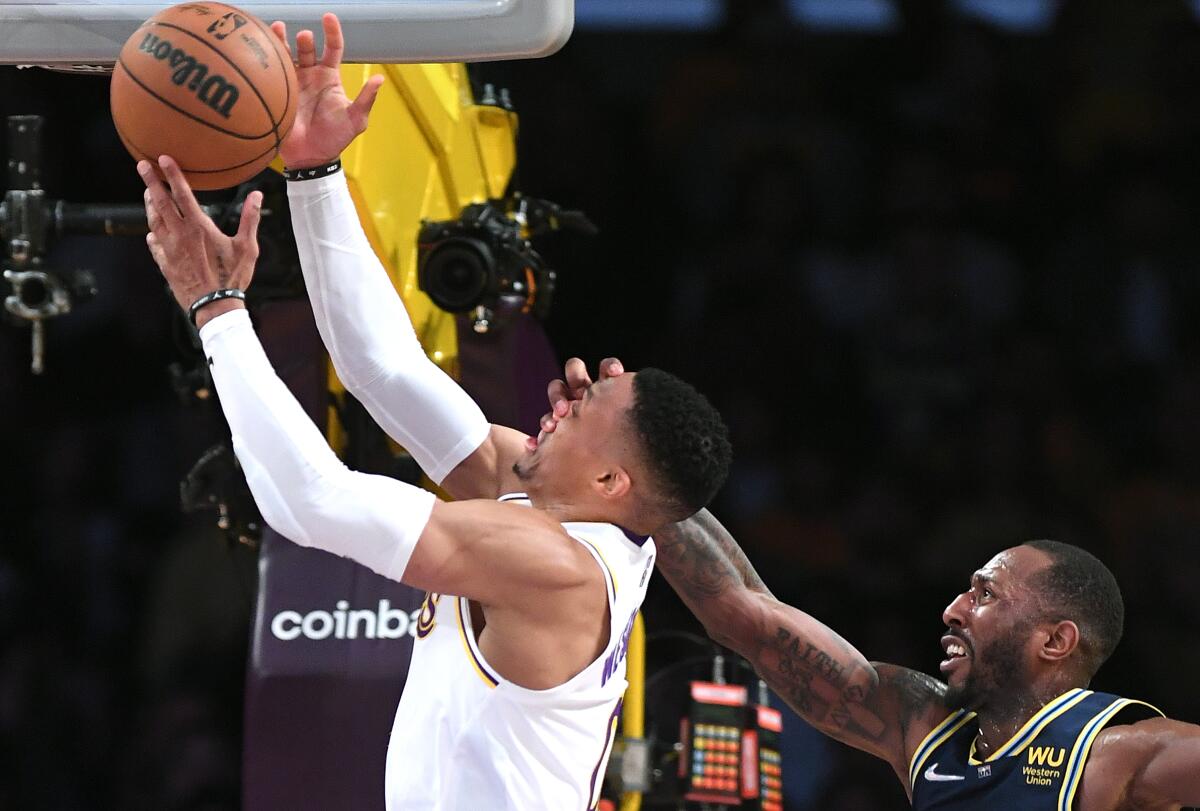 Lakers guard Russell Westbrook attempts a layup as Nuggets guard Davon Reed puts a hand on Westbrook's face.