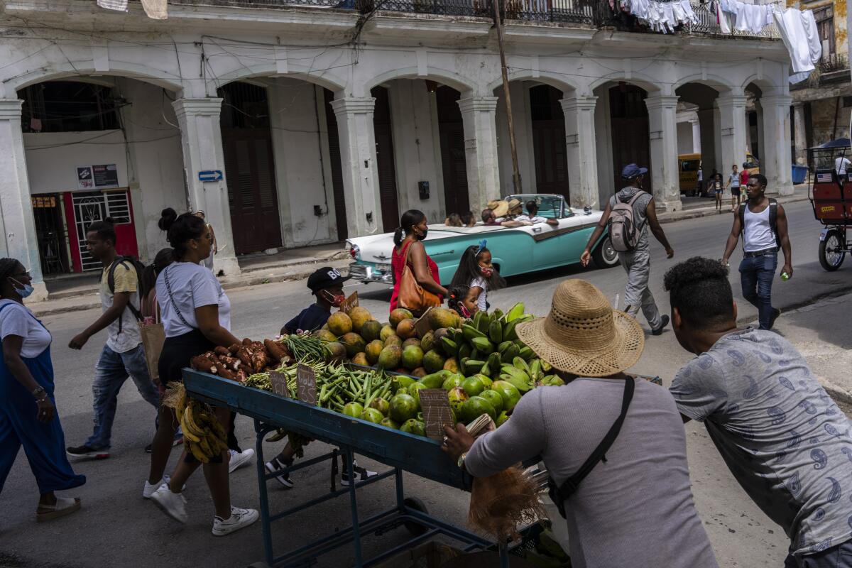 Dos vendedores ambulantes empujan su carrito con frutas y verduras
