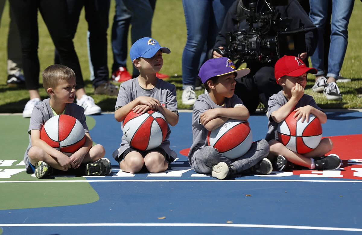 Kids wait to take to the court with new basketballs at Portola Park in Santa Ana.