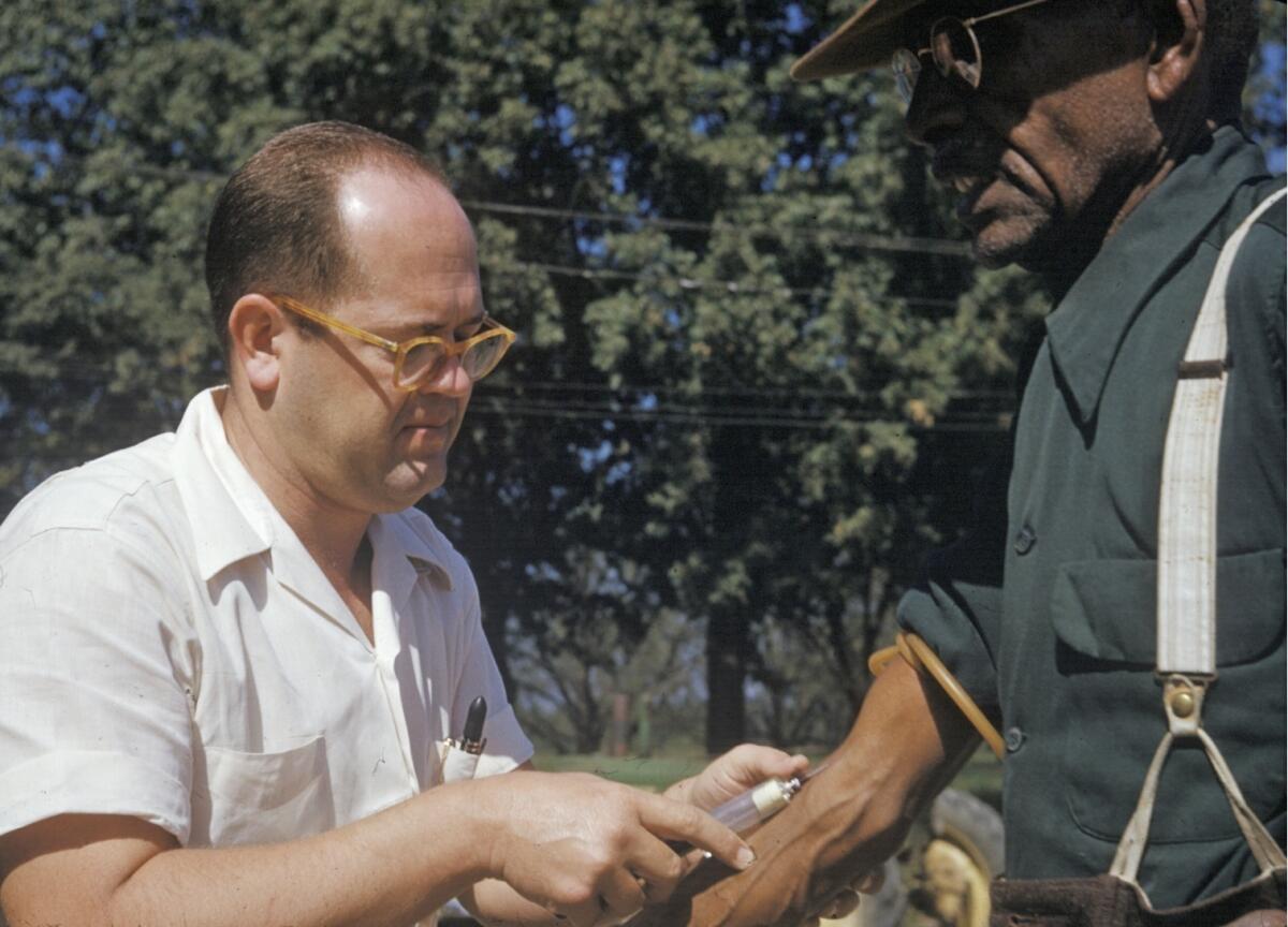A Black man included in a syphilis study has blood drawn by a doctor in Tuskegee, Ala.