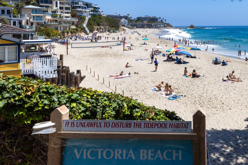 Laguna Beach, CA - June 20: Beach-goers lay on the sand near a roped-off are of the beach in front of a homeowner's house at Victoria Beach in Laguna Beach Thursday, June 20, 2024. The California Coastal Commission sent the Laguna Beach homeowner a letter stating she must remove furniture and a rope fence on the sand in front of the home by Sept. 2 or incur as much as $11,000 per day for each violation. (Allen J. Schaben / Los Angeles Times)