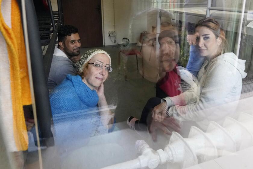 Boshra al-Moallem, bottom left, looks out of the window as she sits in a room with her two sisters and brother-in-law at a refugee center in Bialystok, Poland, on Wednesday, Sept. 29, 2021. After enduring a decade of war in Syria, Boshra al-Moallem and her two sisters seized their chance to flee, but the journey proved terrifying and nearly deadly. Al-Moallem, originally from Homs but who displaced to Damascus by the war, is one of thousands of people who have traveled to Belarus in recent weeks and then found herself helped to cross the border with the help of Belarusian guards, something the EU considers a form of “hybrid war” waged against the bloc with the use of human lives. (AP Photo/Czarek Sokolowski)
