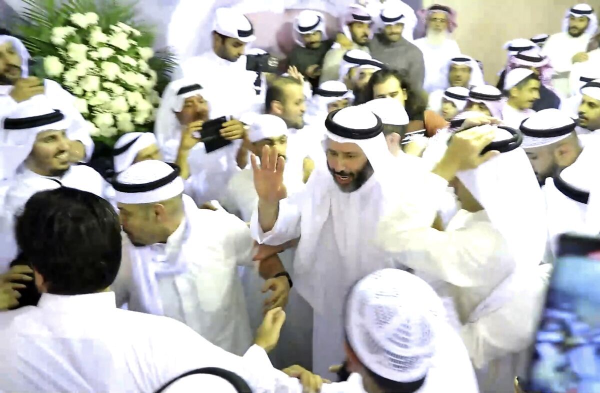 Kuwaiti men in white robes waving and cheering