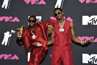 Sean "Diddy" Combs, left, and his son Christian "King Combs" pose in red ensembles with a trophy