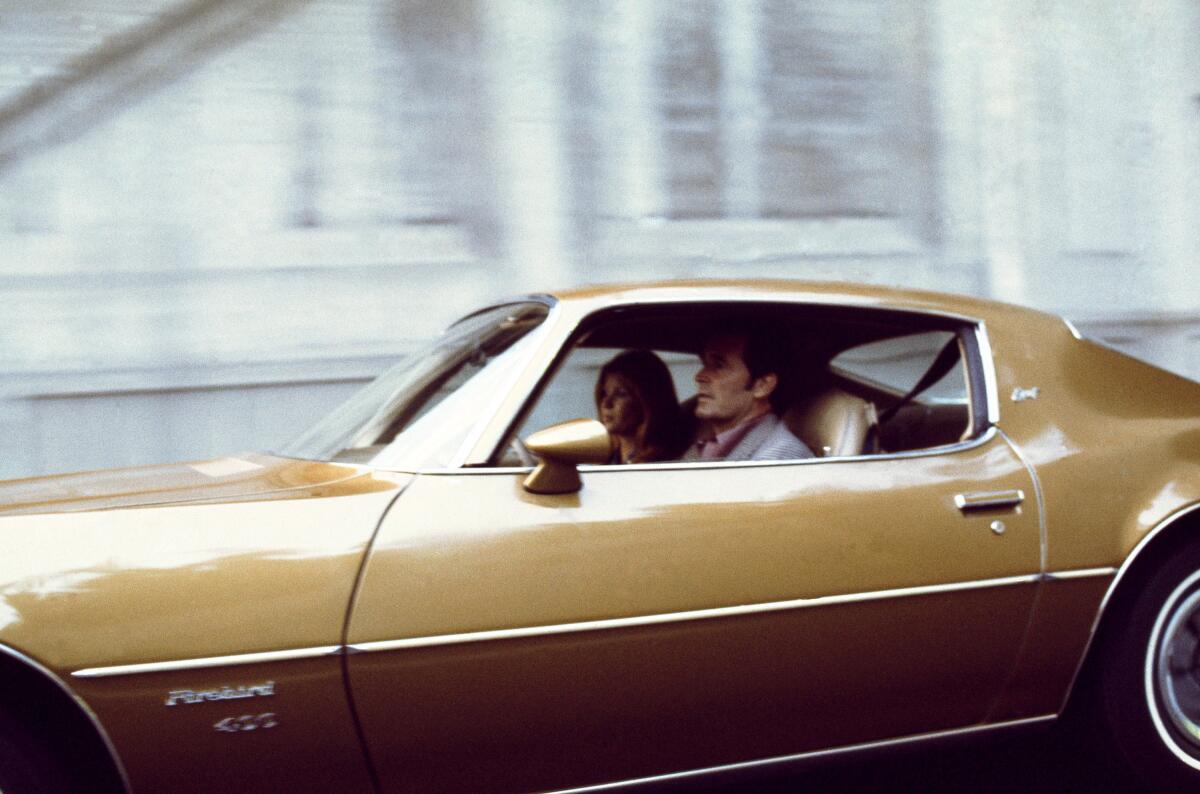 Actors Lindsay Wagner (Sara Butler) and James Garner (Jim Rockford) ride in a Pontiac Firebird.