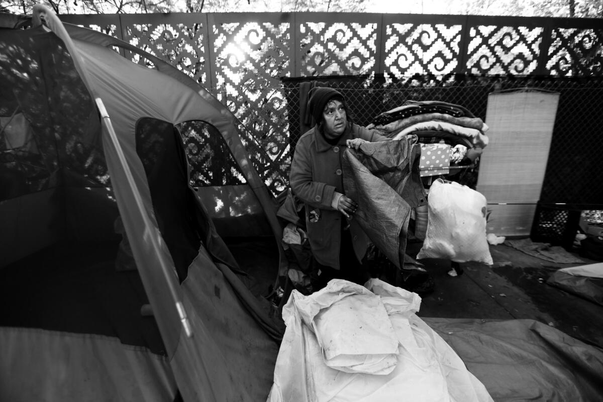 Angel Barros, 48, packs up her tent in preparation for sidewalk cleaning on Spring Street.